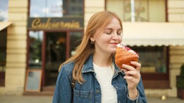 Sabah kahvaltısı. Kahve dükkanının yakınında kruvasan yiyen bir kadın. Yüksek kaliteli FullHD görüntüler