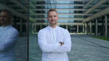 Yakışıklı adam kameraya bakıyor. Yakından pozitif adam kameraya gülümsüyor. Yeşil parktaki kamera önünde poz veren erkek modelin portresi. Neşeli bir adam yüzü ve dışarıda olumlu duygular var. Yüksek kalite FullHD