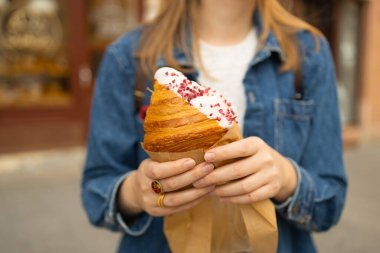 Gülümseyen Avrupalı bayan turist şehir kafesi yakınlarında kahvaltı kruvasanı yiyor. Beyaz kadın, dışarıda rahatlama kokusu alıyor. Yüksek kalite 