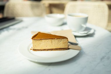 Beyaz beton arka planda klasik New York peynirli keki. Beyaz masada karamelli ve fındıklı lezzetli cheesecake. Yüksek kaliteli FullHD görüntüler