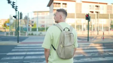 Şık yeşil tişörtlü ve pantolonlu, sokakta yürüyen bir adamın arka plan portresi. Havalı adam sabah yaya geçidinde bekler. Yüksek kaliteli FullHD görüntüler