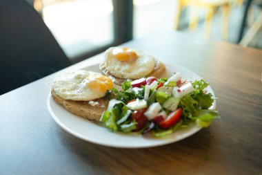 Kızarmış yumurtalı iki tost ve ıspanaklı salata, vişneli domates ve mozzarella kahvaltı masasındaki beyaz tabakta bulunan malzemeler, iştah açıcı vejetaryen yemeği, beyaz arka plan, yakın plan. Yüksek