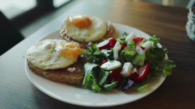 Kızarmış yumurtalı iki tost ve ıspanaklı salata, vişneli domates ve mozzarella kahvaltı masasındaki beyaz tabakta bulunan malzemeler, iştah açıcı vejetaryen yemeği, beyaz arka plan, yakın plan. Yüksek