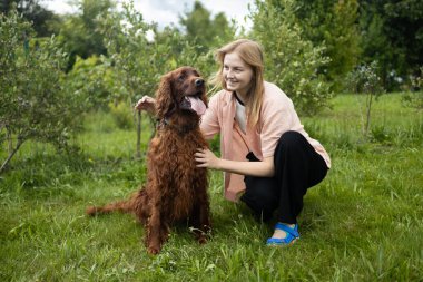 Genç bir kız öğrenci arka bahçede evcil köpeğini okşayıp besliyor ve onunla oynuyor. Yüksek kalite fotoğraf