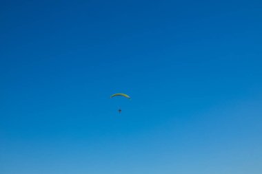 Bulutların arka planında mavi gökyüzünde tek başına uçan bir paraglider. Güneşli bir günde gökyüzünde paraşütle atlamak. Yüksek kalite 