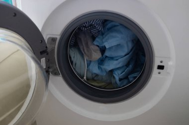 Çamaşır odasında kapısı açık olan modern beyaz çamaşır makinesi, çamaşır odasının içi.