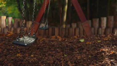 Sonbahar sezonunda parktaki çocuk parkında boş siyah salıncak. Kayıp çocuk. Güneşli bir sonbahar gününde yapayalnız salıncak. Sonbaharda altın yapraklar. Güzel doğa. Yüksek kaliteli FullHD görüntüler