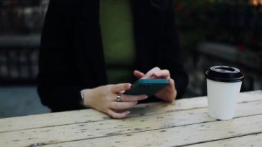 Cep telefonu tutan ve kafede otururken akıllı telefona bakan genç ve güzel bir bayan öğrenci. Mutlu kız cep telefonu kullanıyor ve flört ediyor. Kahve içen, gülümseyen, kafede oturan bir kadın.