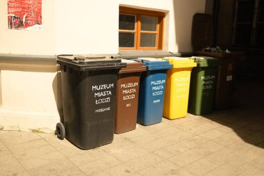 Caddedeki bir binanın yakınındaki çöpleri ayırmak için çok renkli çöp kutuları. Plastik kirliliği sorunu. 