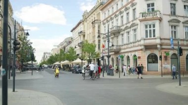 Lodz, Polonya - Mayıs 2024: Tramvaylar ve turistler caddelerden karşıya geçiyor. Yüksek kaliteli Full HD. Yüksek kaliteli FullHD görüntüler