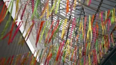 Sıcak bir bahçede rüzgarda renkli süslemeler. Yaz tatili için çok renkli kurdeleler asmak. Sarı ve mavi kurdeleler rüzgarda sallanıyor. Yüksek kaliteli FullHD görüntüler