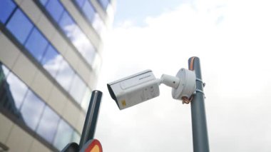 Binanın köşesindeki güvenlik kamerası hareket ediyor ve caddeyi tarıyor. Yüksek kaliteli FullHD görüntüler