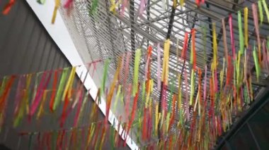 Sıcak bir bahçede rüzgarda renkli süslemeler. Yaz tatili için çok renkli kurdeleler asmak. Sarı ve mavi kurdeleler rüzgarda sallanıyor. Yüksek kaliteli FullHD görüntüler