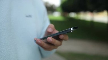 Kapalı çekim adamı, dışarıda güneş ışığında telefonu tutuyor, sosyal ağlara takılıyor, mesajları gönderiyor, akıllı telefondan e-postaları kontrol ediyor ve mobil uygulama sohbeti yapıyor. Yüksek kaliteli FullHD görüntüler