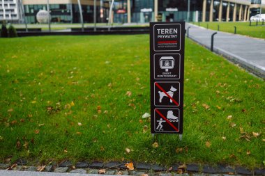 Private land sign Teren private on a green grass lawn in the city. Krakow, Poland clipart