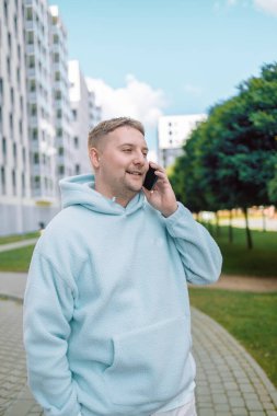  Gülümseyen Kafkasyalı sakallı, gülümseyen, kendine güvenen, caddedeki akıllı telefonda konuşan adam.