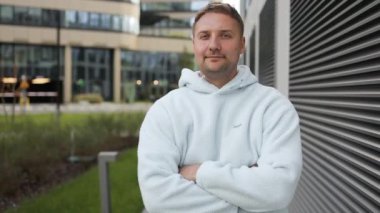 Metal duvar arkasında duran 30 'lu yaşlarda beyaz bir genç. Gülümseyen havalı moda genç öğrenci modeli dışarıda otantik bir portre için poz veriyor yüksek kaliteli fotoğraf.