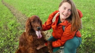 Beyaz kadın dağ tarlasında sevimli İrlandalı Setter köpeğiyle oynuyor. Güzel doğa. Gün batımı. Aile fotoğrafı. Yüksek kaliteli FullHD görüntüler