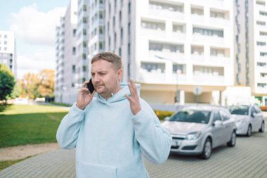 Kafası karışmış Kafkasyalı adam, 30 'lu yaşlardaki adamı hayal kırıklığına uğrattı. Milenyum erkeği, şehir otoparkının yakınındaki stresli araba sürücüsü, kötü haberleri okuyor, cep telefonu sorunu yaşıyor.