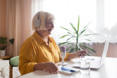 Kadın podcaster akıllı telefon kullanıyor ve mikrofonda izleyicilerle video yayını yapmak için konuşuyor. Yüksek kalite fotoğraf