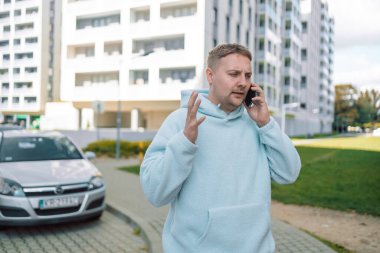 Kafası karışmış Kafkasyalı adam, 30 'lu yaşlardaki adamı hayal kırıklığına uğrattı. Milenyum erkeği, şehir otoparkının yakınındaki stresli araba sürücüsü, kötü haberleri okuyor, cep telefonu sorunu yaşıyor.