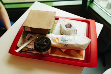 Krakow, Polonya - Mayıs 2023: sokak terasında McDonalds 'tan fast food tepsisi. Kırmızı karton pakette patates kızartması, içinde McDonalds logosu, çizburger, hamburger. Sağlıksız yiyecekler. Yüksek