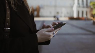 İş kadını elleri gözlüklü Central City caddesinde yürüyor ve telefonunu bir alışveriş merkezinin arka planında kullanıyor..