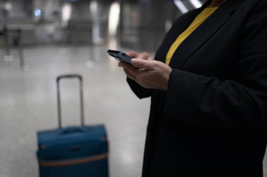 60 'lı yılların Kafkasyalı 50' li yılların kadın yolcusu havaalanındaki cep telefonundan mesaj atıp tatil için havaalanından ayrılmayı bekliyor..