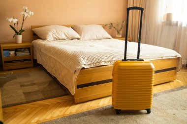 Yatağın yanında sarı valizli otel odasının içi. Otelden otele giriş yaptıktan sonra. Seyahat ve tatil kavramı. Yüksek kalite fotoğraf