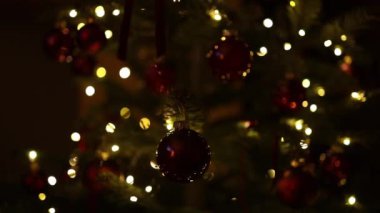 Mutlu yıllar 2025 temalı Noel ağacı dalında kırmızı ve altın toplar süslenmiş güzel ışıklar arka planında. Seçici odak