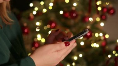 4k Woman akıllı telefonu 2025 yılbaşı Noel tatilinde evde ya da alışveriş merkezinde tutuyor. Noel indirimi, satış ve promosyon için çevrimiçi mağazadan kadın alışverişi. Dikey video