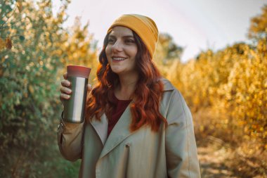 30 'lu yaşlardaki neşeli, rahat, kahve içen ve şehir merkezinde aroma kokan bir kadının fotoğrafı. Yüksek kalite fotoğraf