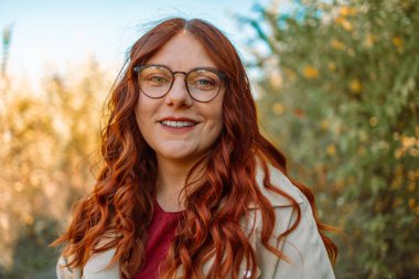 Merhaba Ekim. Çekici kızıl saçlı, şirin yüzlü bir kızın portreleri. Şehir merkezinde kameraya poz veren gözlüklü bir kız. Harika bir ruh hali ve güzel bir gülümsemesi var. Yüksek kalite fotoğraf