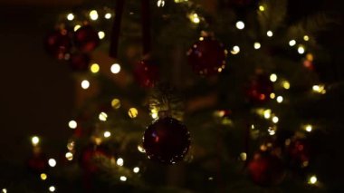 Mutlu yıllar 2025 temalı Noel ağacı dalında kırmızı ve altın toplar süslenmiş güzel ışıklar arka planında. Seçici odak