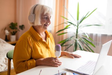 Kadın podcaster akıllı telefon kullanıyor ve mikrofonda izleyicilerle video yayını yapmak için konuşuyor. Yüksek kalite fotoğraf