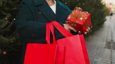 Gülümseyen kadın, geleneksel şehir caddesi Xmas pazarında süslenmiş Noel ağacının arka planında hediye kutularını tutuyor. Hediye değiş tokuşu. Şenlik havası. Festival alışverişi, satış, indirim.. 