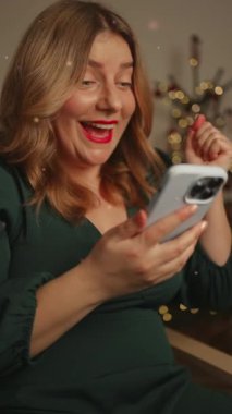 Beyaz kadın bayanın yılbaşı tatilinde evdeki kanepede otururken akıllı telefondan harika haberler almasına şaşırdım. Kız telefonda hoş bir mesaj okuyor.