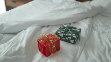 Kırışmış beyaz yatak çarşafları üzerine kağıt kaplı iki xmas sürpriz hediyesi. Yüksek kaliteli FullHD görüntüler