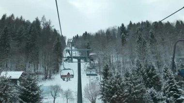 Kayak merkezindeki iskemle kaldırma ile karlı dağ kış ormanı üzerinde hava manzarası. Kayak asansörlü teleferik, İHA 'dan aşağı. Karla kaplı ağaçlarla kaplı kış manzarası. Açık havada kayak sporu.