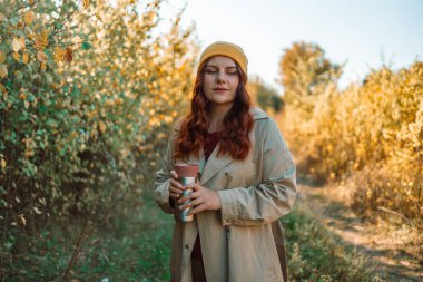30 'lu yaşlardaki neşeli, rahat, kahve içen ve şehir merkezinde aroma kokan bir kadının fotoğrafı. Yüksek kalite fotoğraf