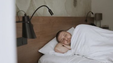 İyi sabahlar. Tembel adam mutlu bir şekilde sabah elleri pencereye kaldırarak uyanır ve rahatlar. Yüksek kaliteli FullHD görüntüler