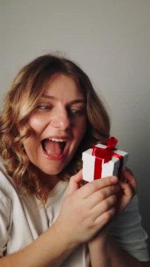 Bej arka planda Sevgililer Günü için hediye kutusu olan güzel, genç, pozitif bir kadın.