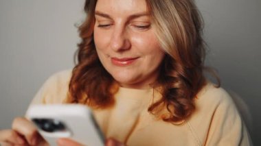 İş kadını cep telefonu kullanıyor. Avrupalı iş kadını CEO 'su elinde akıllı telefon tutarak Fintech uygulamasını ofiste ayakta tutuyor. Yüksek kaliteli FullHD görüntüler