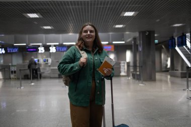 Uluslararası havaalanı terminali. Modern havaalanı terminalinde sırt çantalı, 30 'lu yaşlarda, mutlu beyaz kadın gezgin. Turist yolculuğu konsepti