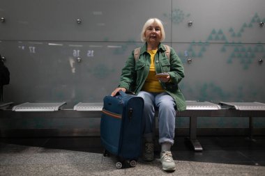 Bir pasaport, uçak bileti ve belgeler havaalanında elde tutulan bir bavulda yatıyor. Arka koltukta oturan bir kadın uçağını bekliyor. Yüksek kalite fotoğraf