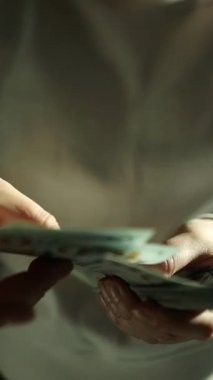 Isıtıcının yanında oturan bir kadın, dolarları endişeden sayıyor. Artan faturalar ve fiyatlar, enerji krizi büyüdükçe strese yol açıyor. Finansal kararlar ağır gelir. Yüksek kalite FullHD