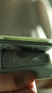 Vergi belgelerini incelerken 100 dolarlık banknotlar sayan bir kadın. Finansal planlama ve vergi hazırlama kavramı. Dünya ekonomisi. Döviz bürosu. Nakit ödeme. Yüksek kaliteli FullHD görüntüler