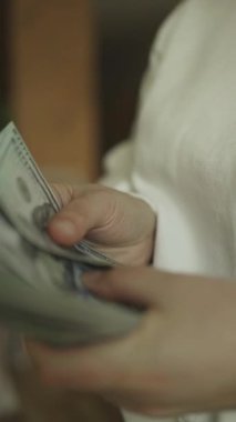  Adam bize 100 dolarlık banknotları sayarak para veriyor. Tasarruf kavramı. Yüksek kaliteli FullHD görüntüler