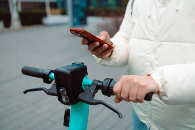 Akıllı telefon uygulaması kullanan yakışıklı bir adam. Eleman elektrikli scooter 'a yaklaşır ve park yerindeki bisiklet parkında NFC uygulamasını kullanır. Yüksek kalite fotoğraf