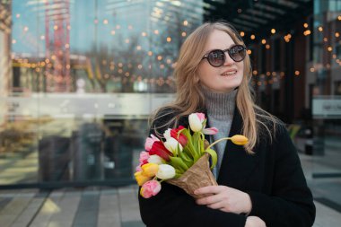 Güzel, mutlu, beyaz bir kadın. Gözleri kapalı laleler kokluyor. Yüksek kalite 